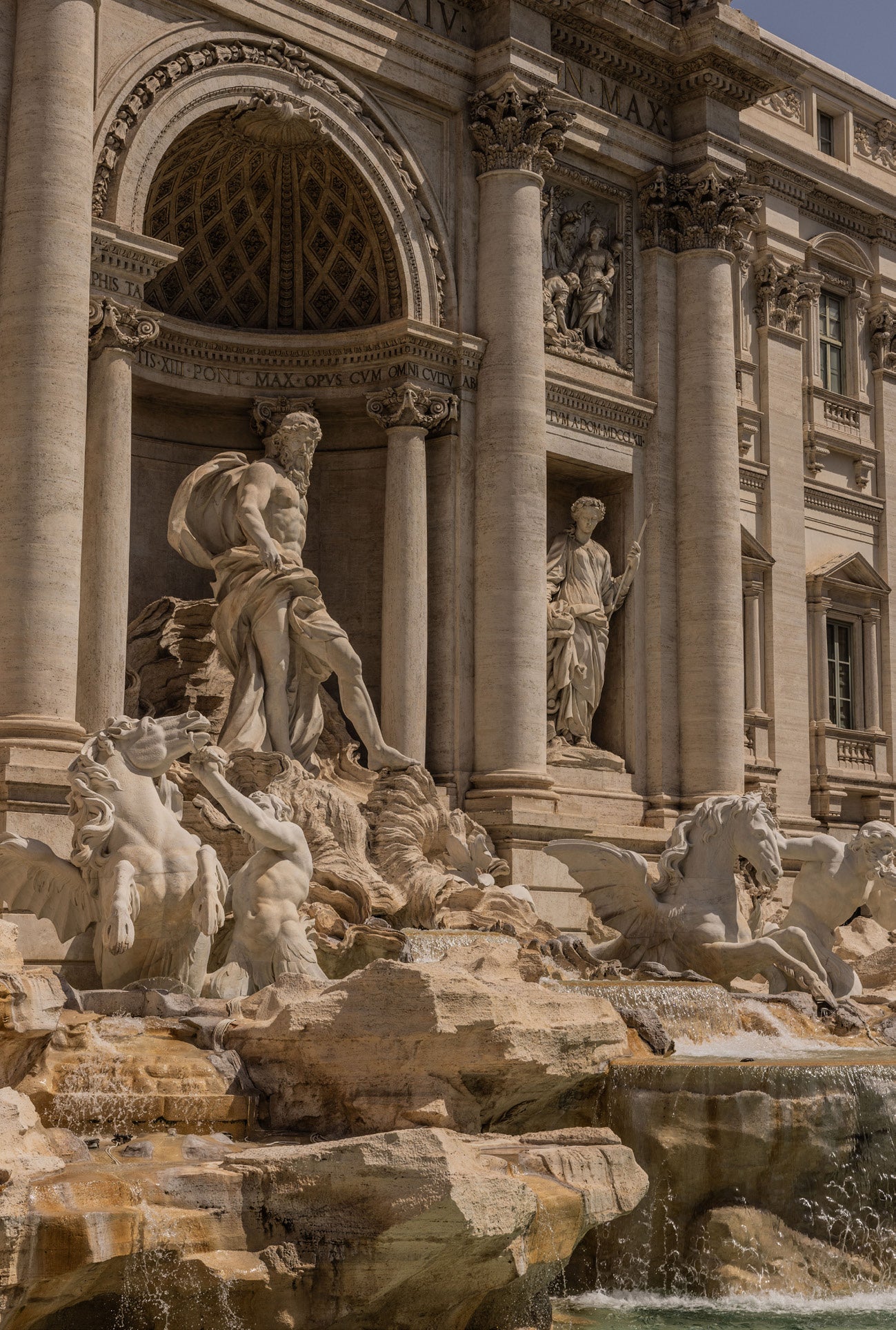 Close-up of the Trevi Fountain in Rome showing the Baroque marble sculptures of Neptune and tritons with ornate columned facade